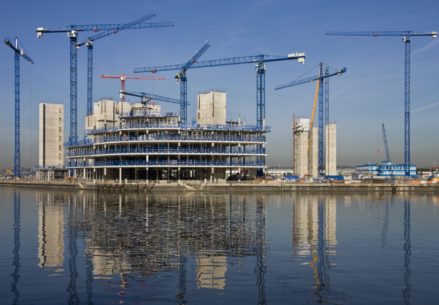 Construction cranes building a waterside office development
(In Salford Quays in Greater Manchester in Great Britain)